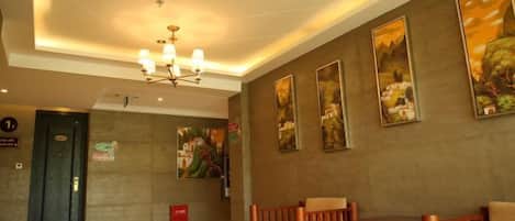 A lobby with a reception desk, seating area, and artwork on the walls.