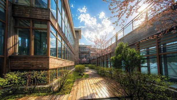 Un edificio moderno con ventanas amplias y una terraza de madera.