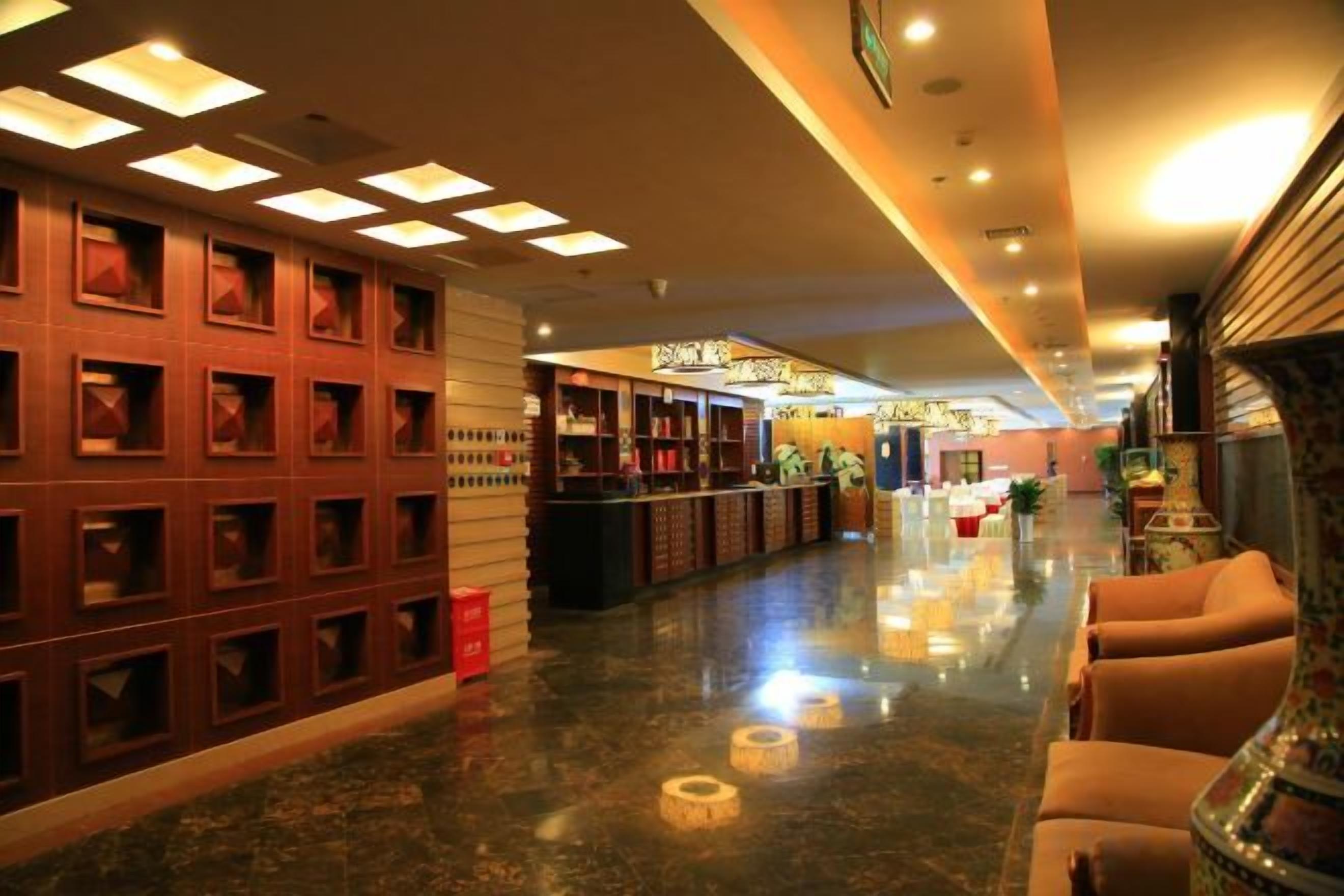 A hotel lobby with a reception desk, seating area, and a decorative wall with recessed lighting.