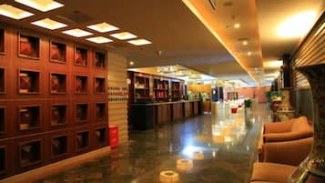 A hotel lobby with a reception desk, seating area, and a decorative wall with recessed lighting.
