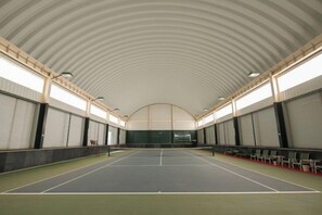 An indoor tennis court with a high, curved ceiling and walls lined with windows. - Xinhua Hotel Fairy Mountain (Chongqing)