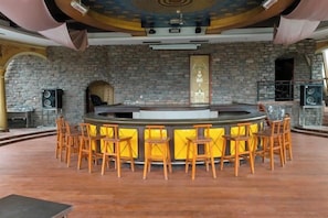 A bar area with a stone wall backdrop, a central bar counter, and wooden bar stools. - Xinhua Hotel Fairy Mountain (Chongqing)