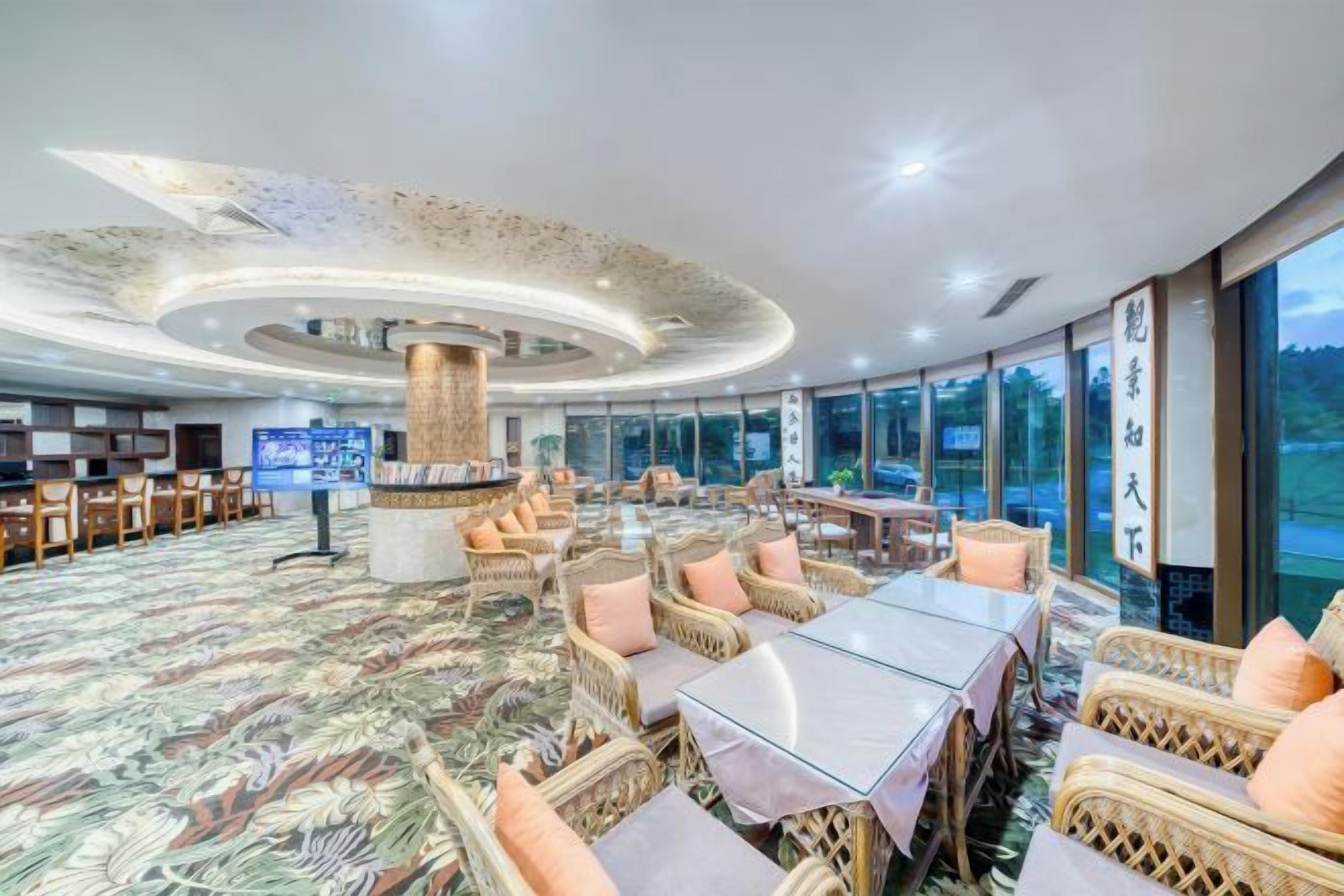 A spacious hotel lobby with a central column, seating arrangements, and large windows offering a view.
