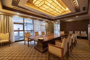 Un salón de conferencias con una gran mesa, sillas y vistas amplias a través de ventanales.