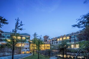 Un hôtel moderne, doté de plusieurs étages, de grandes fenêtres et d’une façade bien éclairée.