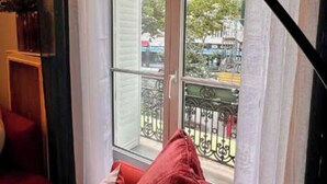 A room with a red sofa, a window with a view of buildings and trees, and a metal railing outside. - Elegant Apartement - AC 2br-6p- Palais des Congres (Paris)