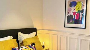 A hotel room with a bed, pillows, a framed artwork, and a rolled towel on the floor. - Elegant Apartement - AC 2br-6p- Palais des Congres (Paris)