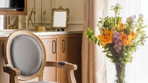 A room with a wooden chair, a small round table, a mirror, and a vase with flowers. - Merveil - Luxury Suite - Marais - Turenne (Paris)