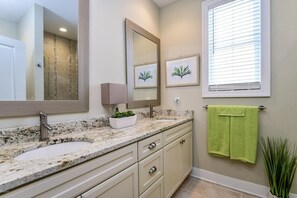 A bathroom with a granite countertop, two sinks, a large mirror, a potted plant, and a window with blinds. - Third Coast Hideaway - Saugatuck - Douglas Downtown Area - Spacious & Spotless (Douglas)