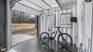 A bike storage area with a bicycle, maps on the wall, and a metal ladder.