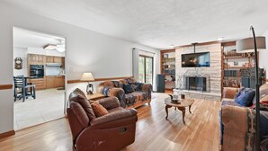 Un amplio salón con chimenea, sofás de cuero y televisor.