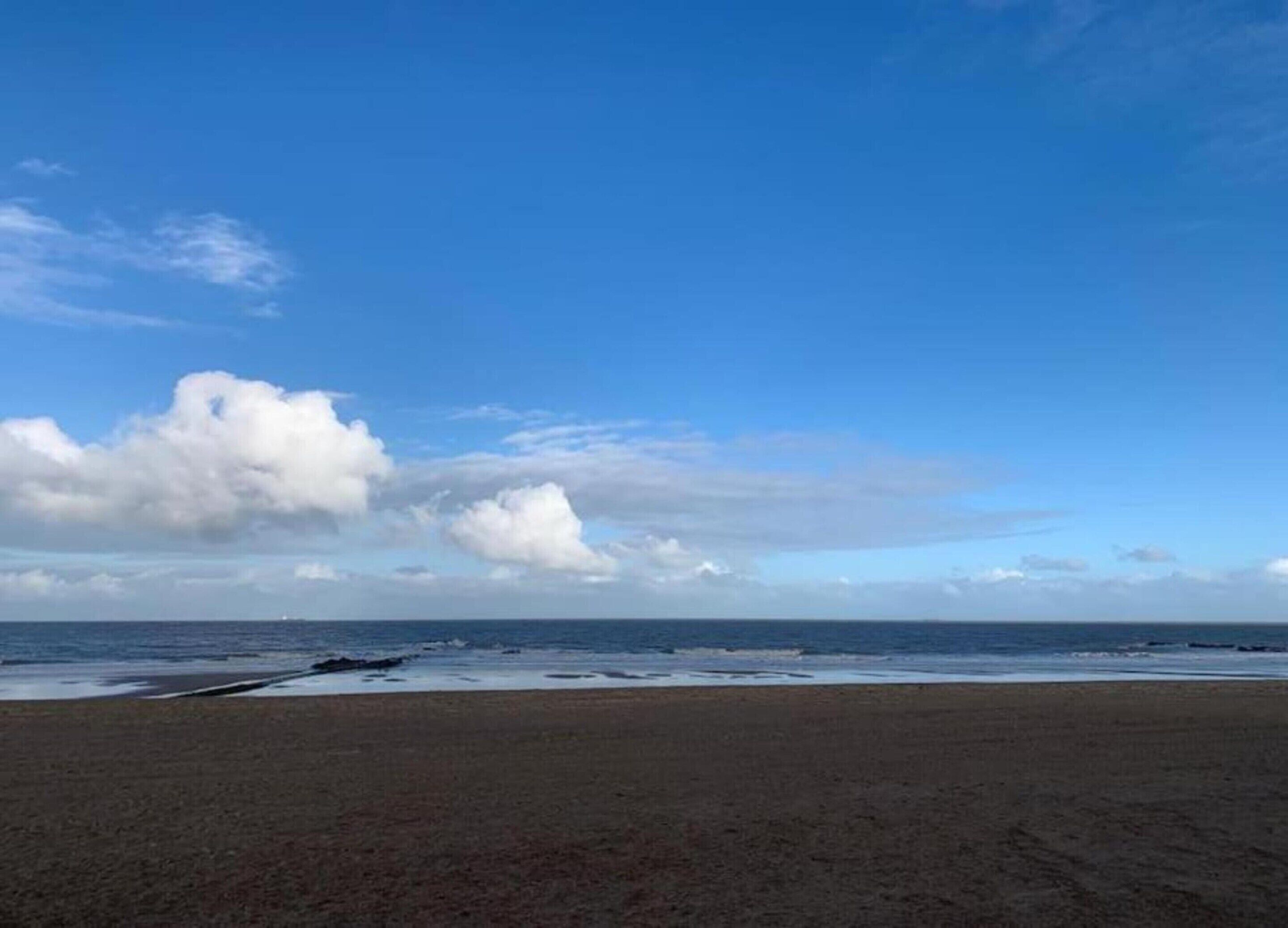 Una playa con cielo despejado y mar tranquilo.