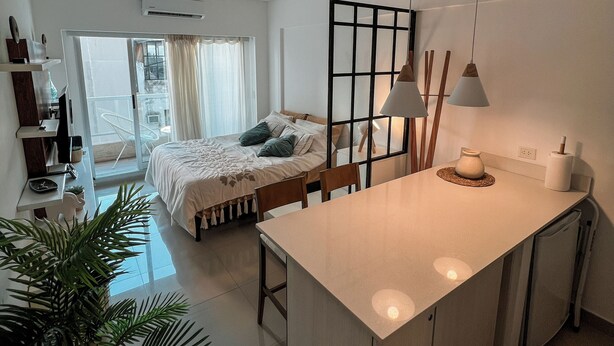 A modern, well-lit room with a large island, a bed with a view, and a dining area. - Charm and comfort in the heart of the historic center. (Buenos Aires)