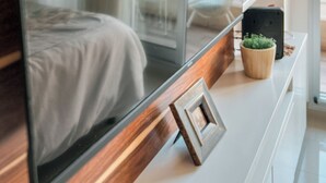 A modern room with a large flat-screen TV mounted on a wooden wall, a small potted plant, and a framed picture on a white console table. - Charm and comfort in the heart of the historic center. (Buenos Aires)