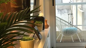 A modern interior with a white console table, potted plants, and a white chair by a large window. - Charm and comfort in the heart of the historic center. (Buenos Aires)