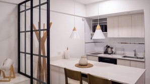 A modern kitchen with a white countertop, wooden chairs, a pendant light, and a microwave. - Charm and comfort in the heart of the historic center. (Buenos Aires)