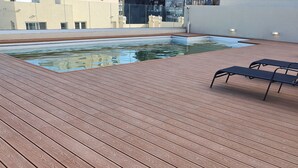 A rooftop pool with wooden decking and lounge chairs. - Charm and comfort in the heart of the historic center. (Buenos Aires)