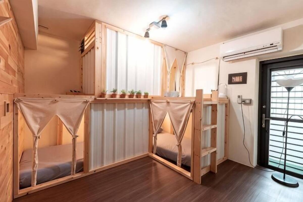 A room with a wooden partition, a small window, a door, and a wall-mounted air conditioner.