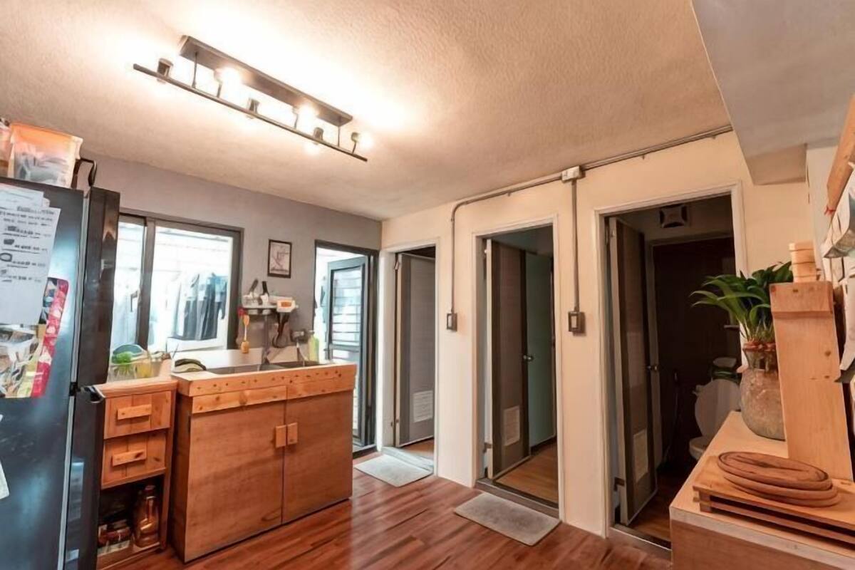 A kitchen with wooden cabinets, a refrigerator, and a countertop. There are sliding doors leading to another room.
