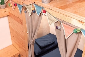 A wooden cabin with a bed, curtains, and a small table with a plant. - Yilan Inspiration (Yilan)