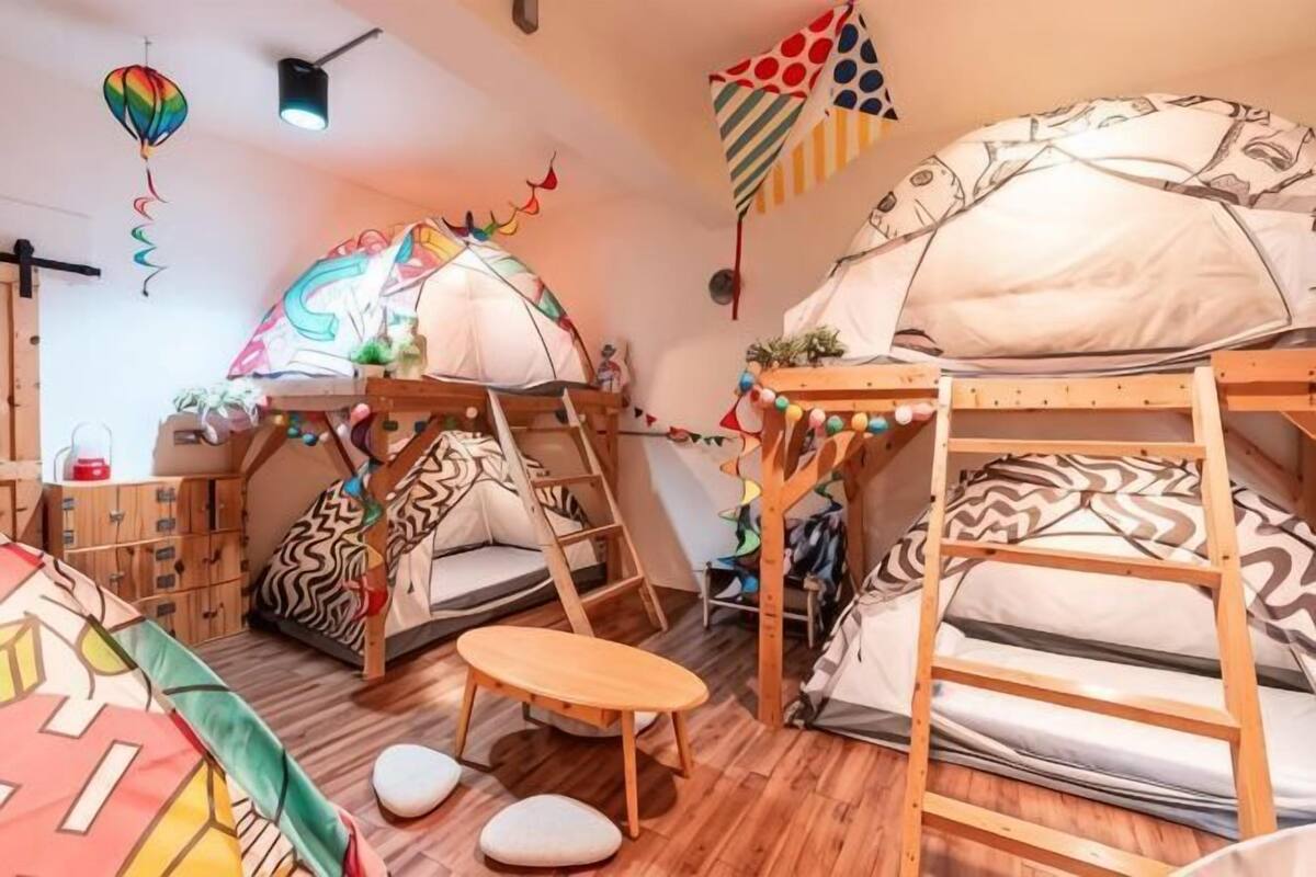 A room with bunk beds, a small table, and a tent-like structure.