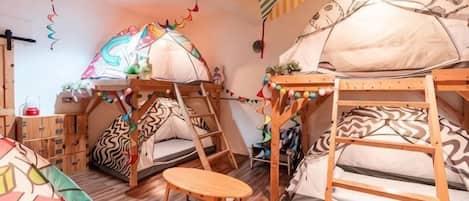 A room with bunk beds, a small table, and a tent-like structure.