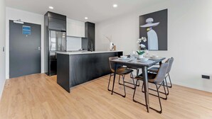A modern kitchen with a central island, a dining area with a table and chairs, and a wall-mounted artwork. - Penthouse 3BR & 2Bath-Skytower View-Pool, Parking (Auckland)