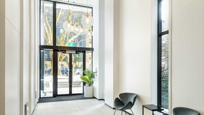 A modern lobby with a glass door entrance, a potted plant, and two black chairs. - Penthouse 3BR & 2Bath-Skytower View-Pool, Parking (Auckland)