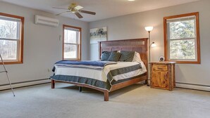 A bedroom with a wooden bed, a ceiling fan, and a nightstand.