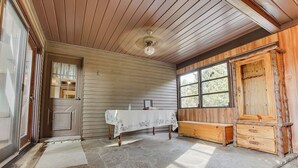 A room with wooden walls, a stone floor, a table with a white tablecloth, a bench, and a wooden cabinet.