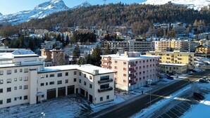 A snow-covered town with buildings, a road, and mountains in the background.