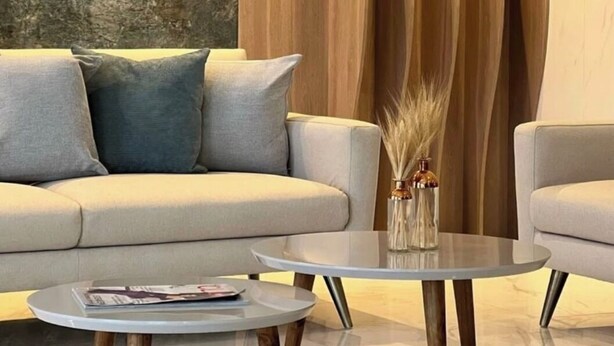 A modern living room with a sofa, two round coffee tables, and a textured wall.