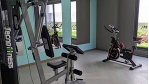 A gym with cardio machines, a weight bench, and a mirror.