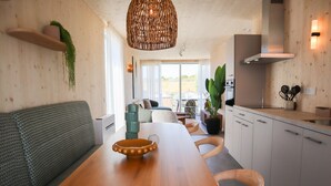 Una cocina moderna con una mesa de comedor de madera, armarios blancos y una lámpara colgante.