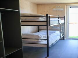 Habitación con literas, pared de madera y una puerta que da al exterior.