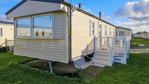 A mobile home with a front porch, large windows, and a chimney. - 3 bedroom accommodation in Rhyl (Rhyl)