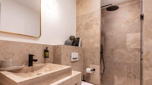 Een moderne badkamer met een beige marmeren wastafel, toilet en douche.
