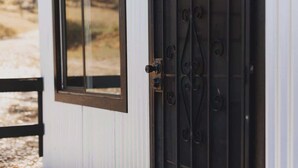 Una porta blanca amb una reixa de metall negra i una finestra.