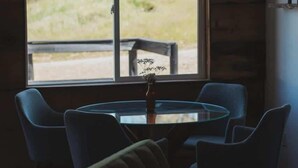 Habitació amb taula rodona i quatre cadires, finestra amb vista a vegetació i ventilador de sostre.