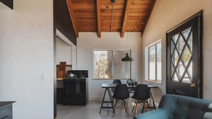 Una cucina moderna con zona pranzo, un divano e un'ampia finestra vista alberi.