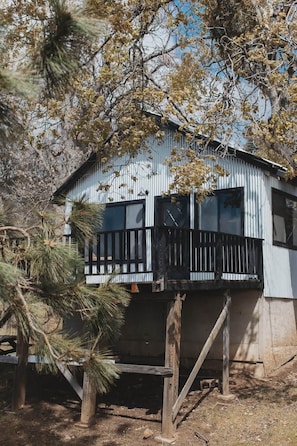 A two-story building with a balcony, surrounded by trees. - Secluded rustic 1-bedroom cabin on private land (Dunlap)