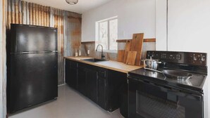 Una cucina moderna con un frigorifero nero, un lavello, taglieri in legno e un piano cottura.