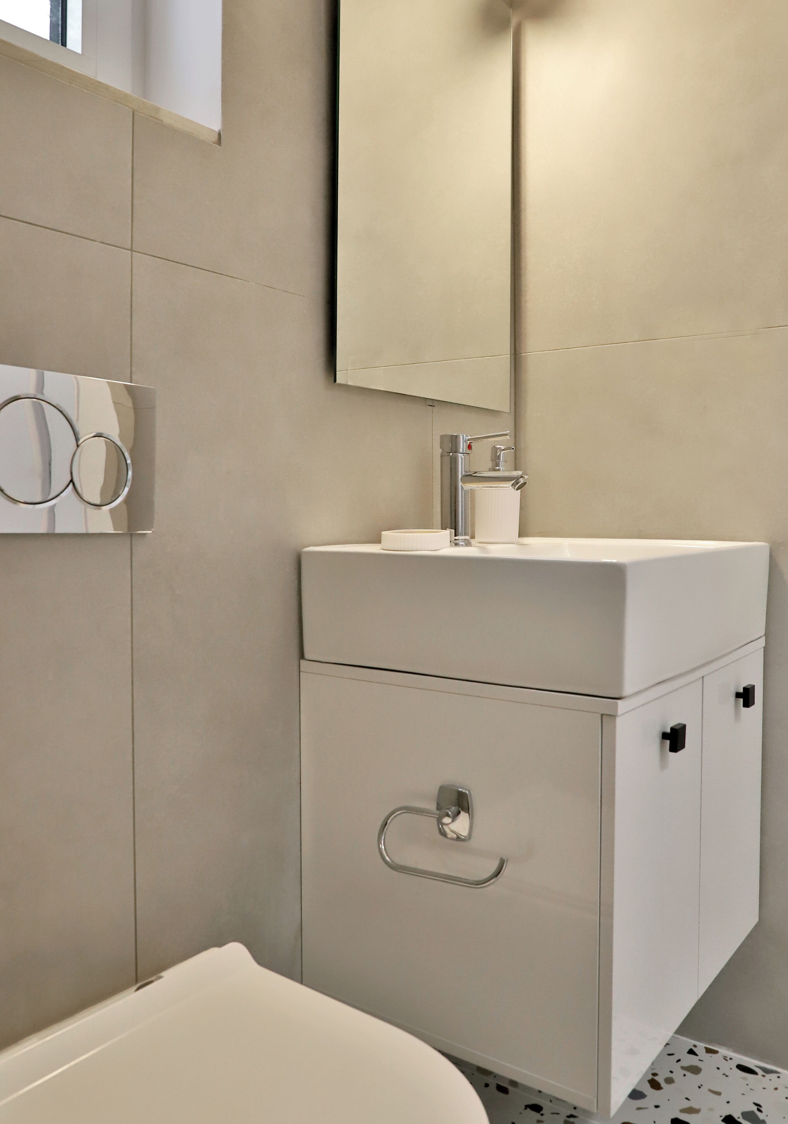 Un baño moderno con un lavabo blanco, un espejo y un inodoro.