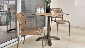 A balcony with a table and two chairs, a potted cactus, and a view of the outside. - Centro Apartments By Comfortbnb (Sitia)