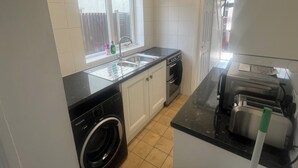 A kitchen with a washing machine, a sink, and a toaster. - Elegant Escape (Coseley)