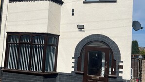 A two-story house with a bay window, a front door with an arch, and a satellite dish. - Elegant Escape (Coseley)