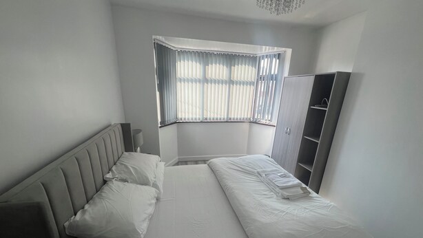 A bedroom with a bed, a wardrobe, and a window with blinds. - Elegant Escape (Coseley)