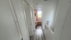 A narrow hallway with wooden flooring and white walls. - Elegant Escape (Coseley)