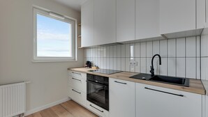 A modern kitchen with white cabinets, a wooden countertop, a black sink, and a window providing natural light.