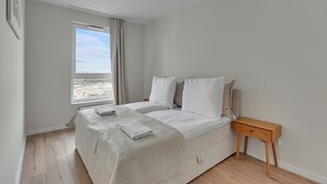 A bedroom with a bed, a nightstand, a window, and a view of the outdoors.